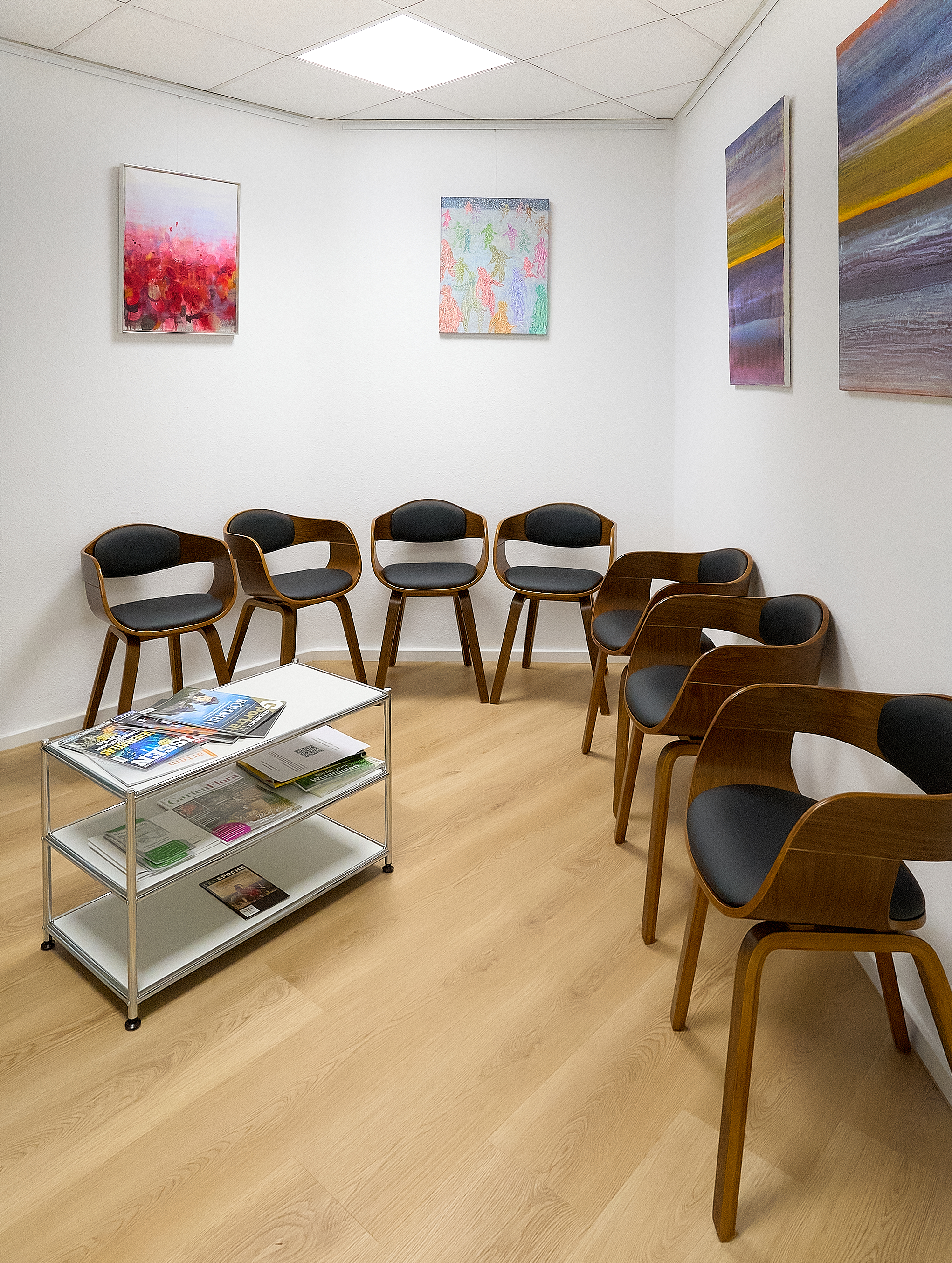 Wartezimmer mit Sitzreihe und abstrakten Gemälden
